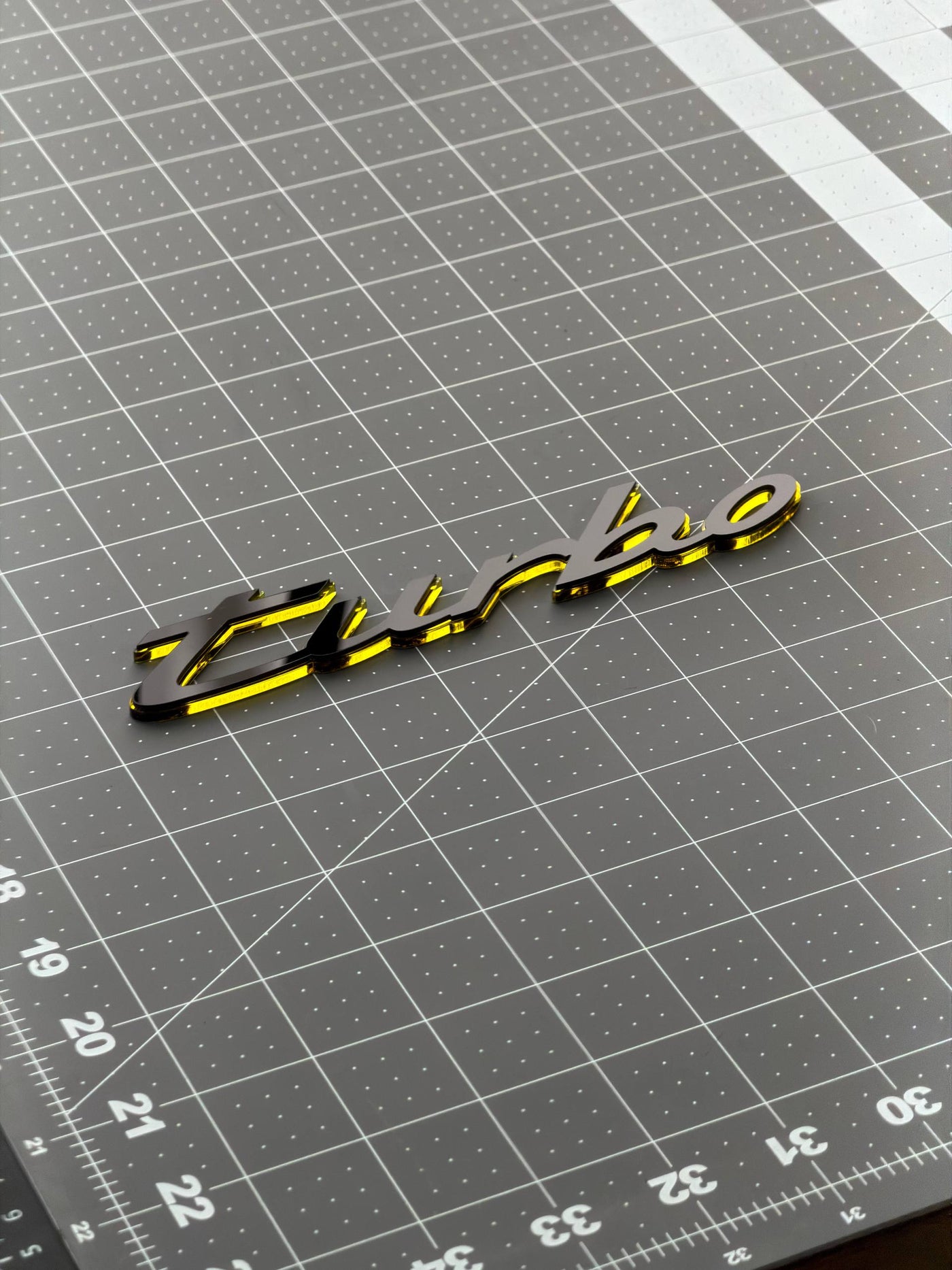 An acrylic model script laid on a cutting mat, measured before it is fitted to a car