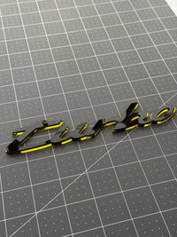 Gloss black face of the Porsche turbo emblem over its mirrored base layer